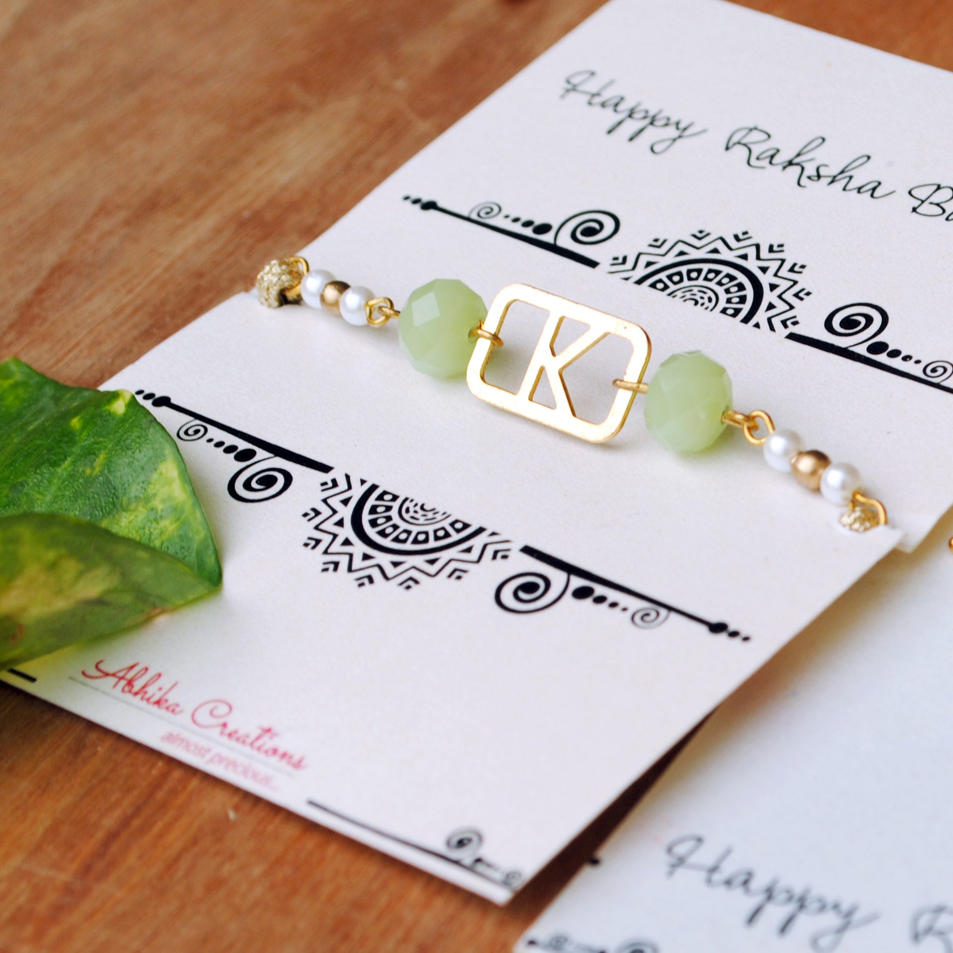 BeAbhika Green Pearl Personalised Initial Rakhi Gold Tone Lightweight Easy To Tie Customised Name Letter Rakhi Available At Best Price In India Online COD Available Send Rakhi To Brother Small Brother Big Brother Younger Brother Send Rakhi Abroad With Roli Chawal Capsules Designer Unqiue Famous