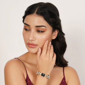 Top view of navy blue bead bracelet with a rectangular glass stone, floral Kundan motifs and adjustable gold-tone chain.