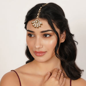 Top view of floral Kundan maangtikka with pearls, featuring round glass stones, gold bead fringe and a pearl-accented chain.