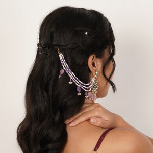 Top view of purple beaded hairchains with three draped pearl strands, oval glass drops and gold-tone hook closures.