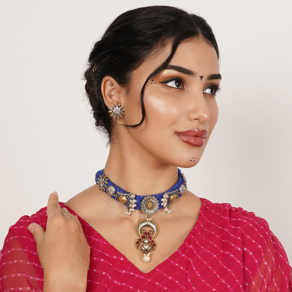 A woman wearing a blue and gold beaded choker necklace with a matching statement earring