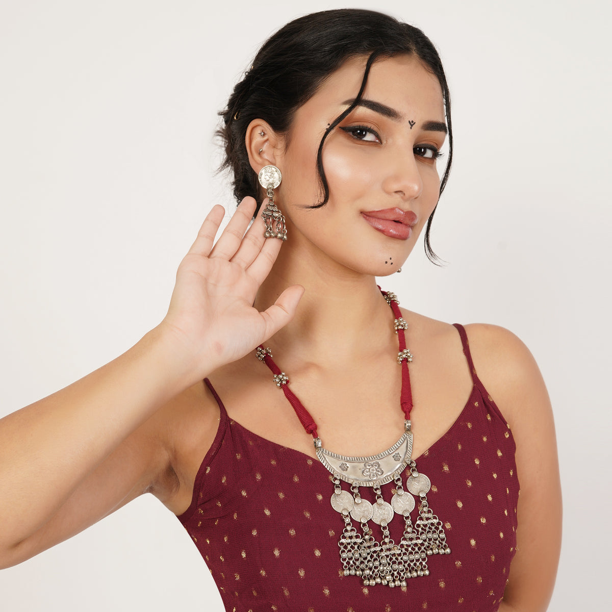 A woman wearing a traditional Indian silver-toned necklace with a large semicircle pendant and matching dangling earrings