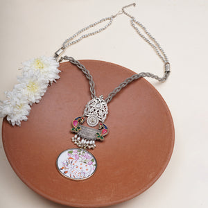 A silver-toned necklace with a detailed pendant featuring a silver elephant, colorful enamel accents, and a round floral pendant