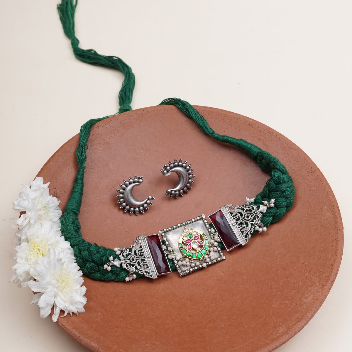 A green braided necklace with ornate silver-toned metal accents and a central decorative panel