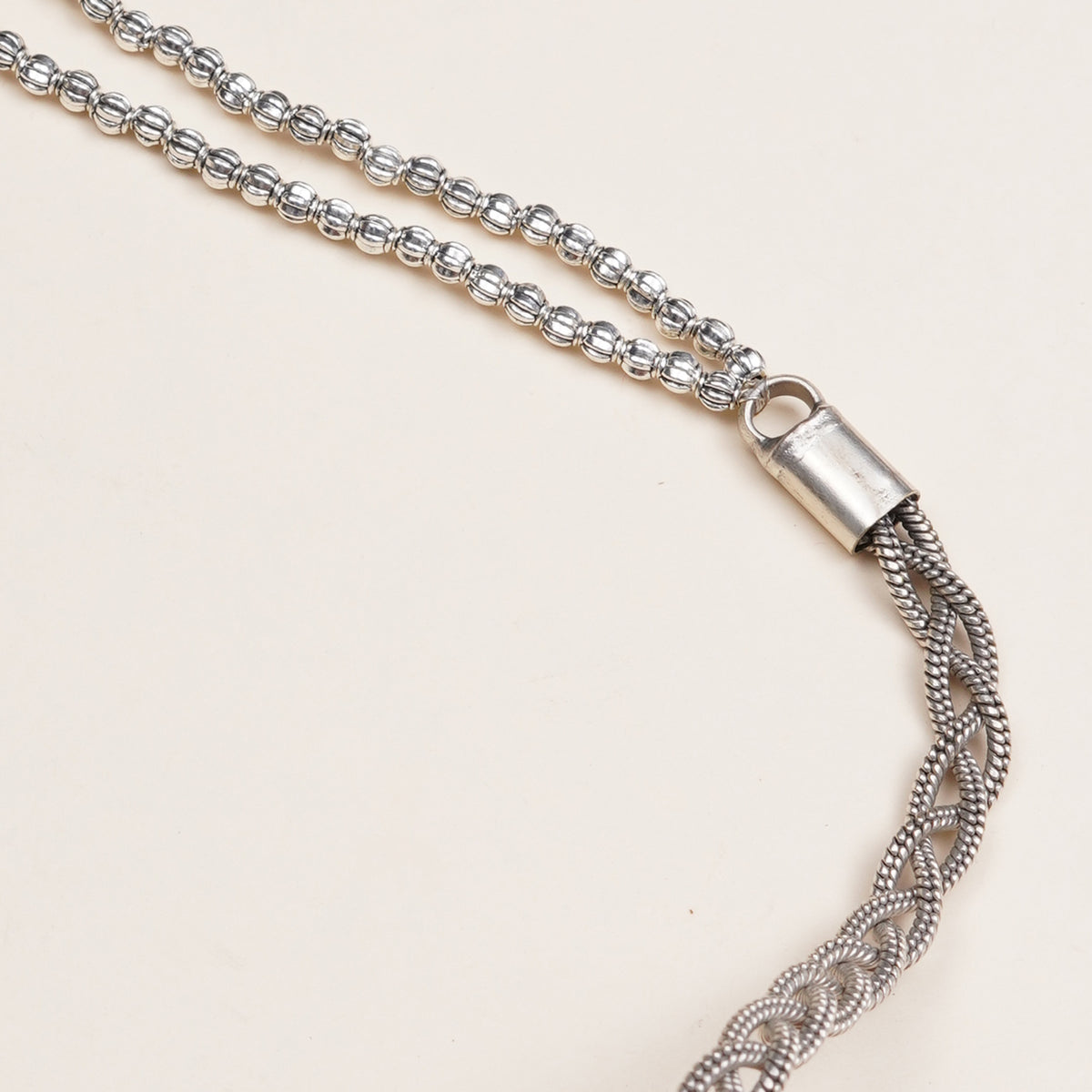 Silver-toned beaded chain necklace with a cylindrical clasp and a braided tassel