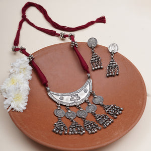 A traditional Indian silver necklace and matching earrings with red cord.