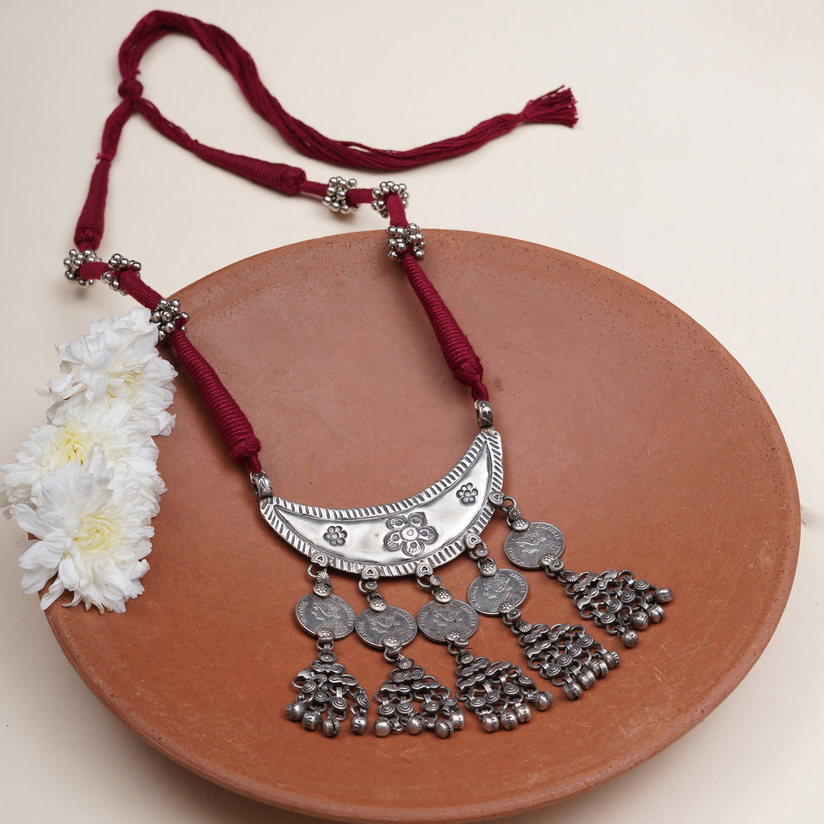 A traditional Indian silver crescent collar necklace with dangling coins and tassels.