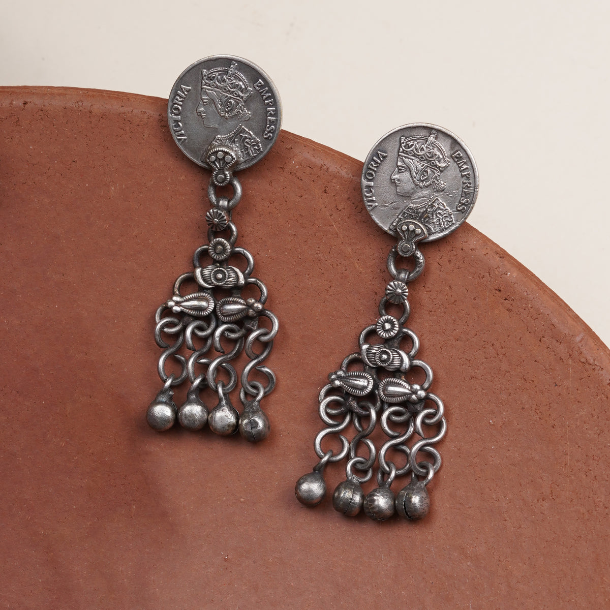 A pair of silver-toned dangle earrings with coin-shaped studs.