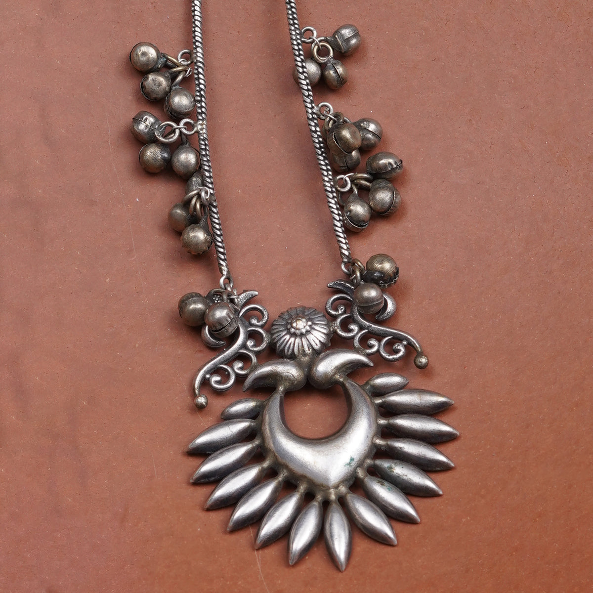 An antique silver-toned earring featuring a crescent moon earring with radiating petal-like points, decorative scrollwork, and clusters of small round beads