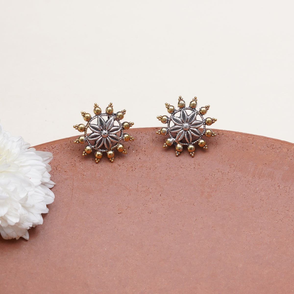 A pair of starburst stud earrings with silver-toned centers and gold-toned outer points