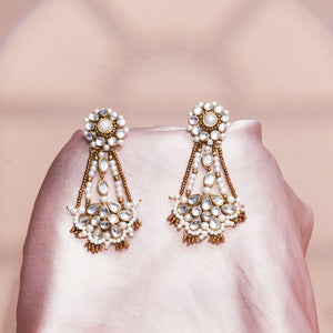 A pair of ornate gold-toned statement earrings with white faux pearls and clear rhinestones.