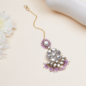Floral Kundan maangtikka with purple drops, featuring pear-shaped glass stones, purple beads and gold-tone mixed alloy.